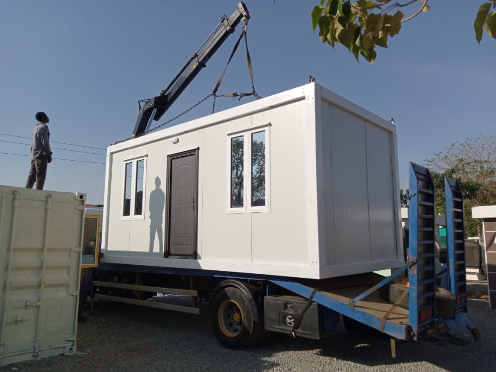 Completed container house being craned onto a truck for delivery