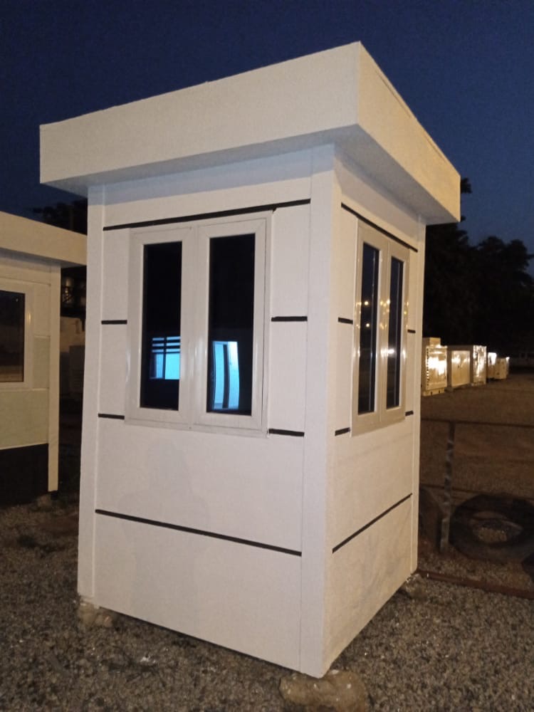 Compact white panel cubicle unit with windows at dusk