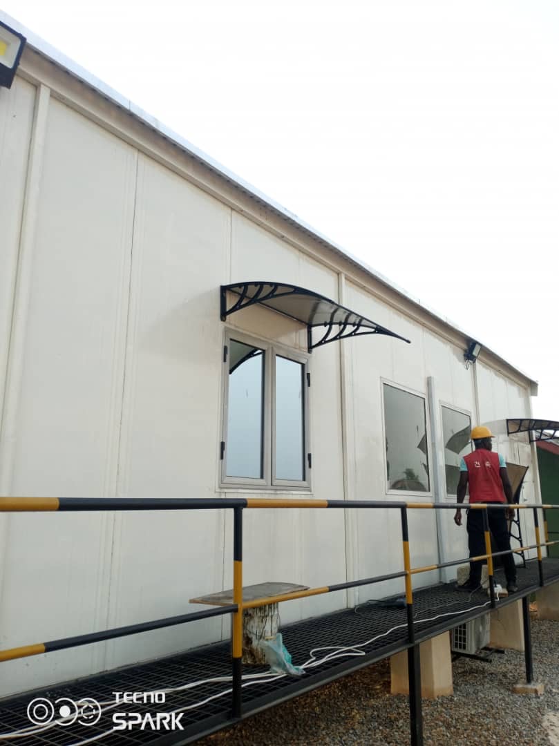 Long white panel office building with window awnings and an access ramp