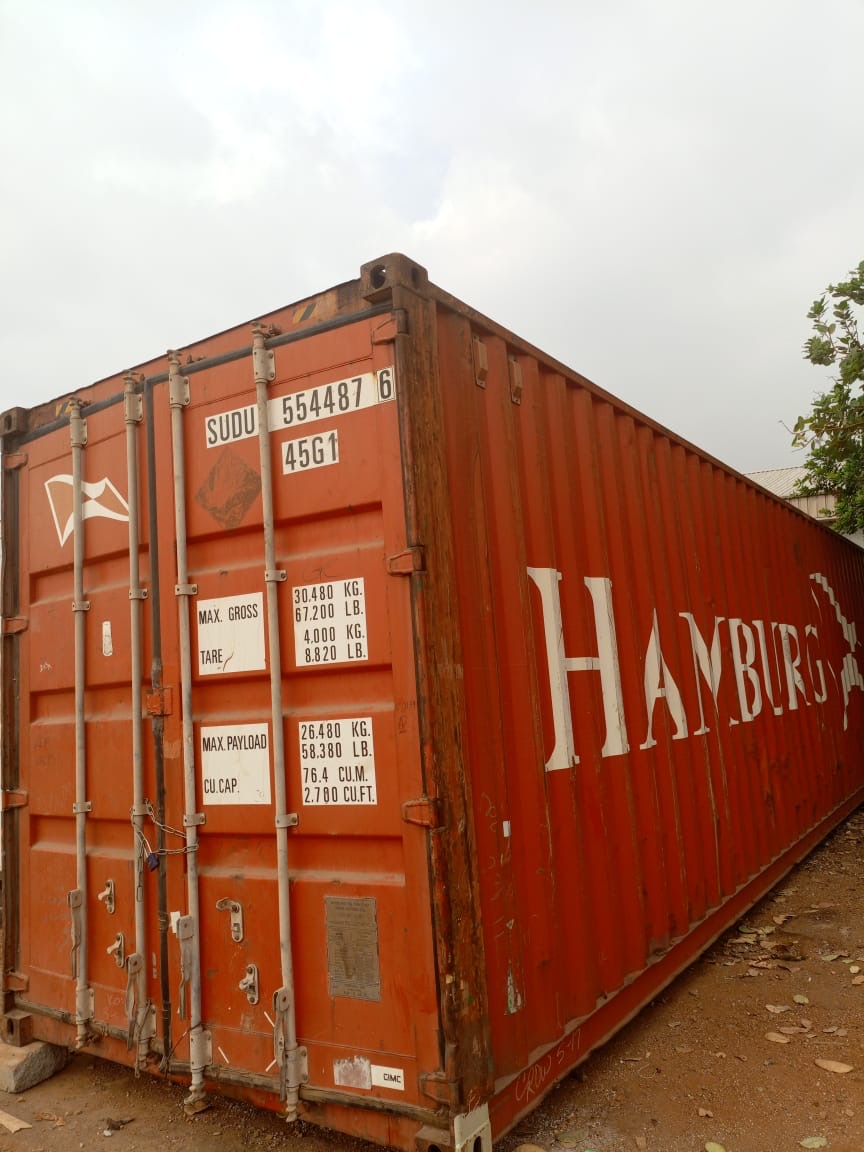 A 40ft shipping container standing on the ground, side and door view