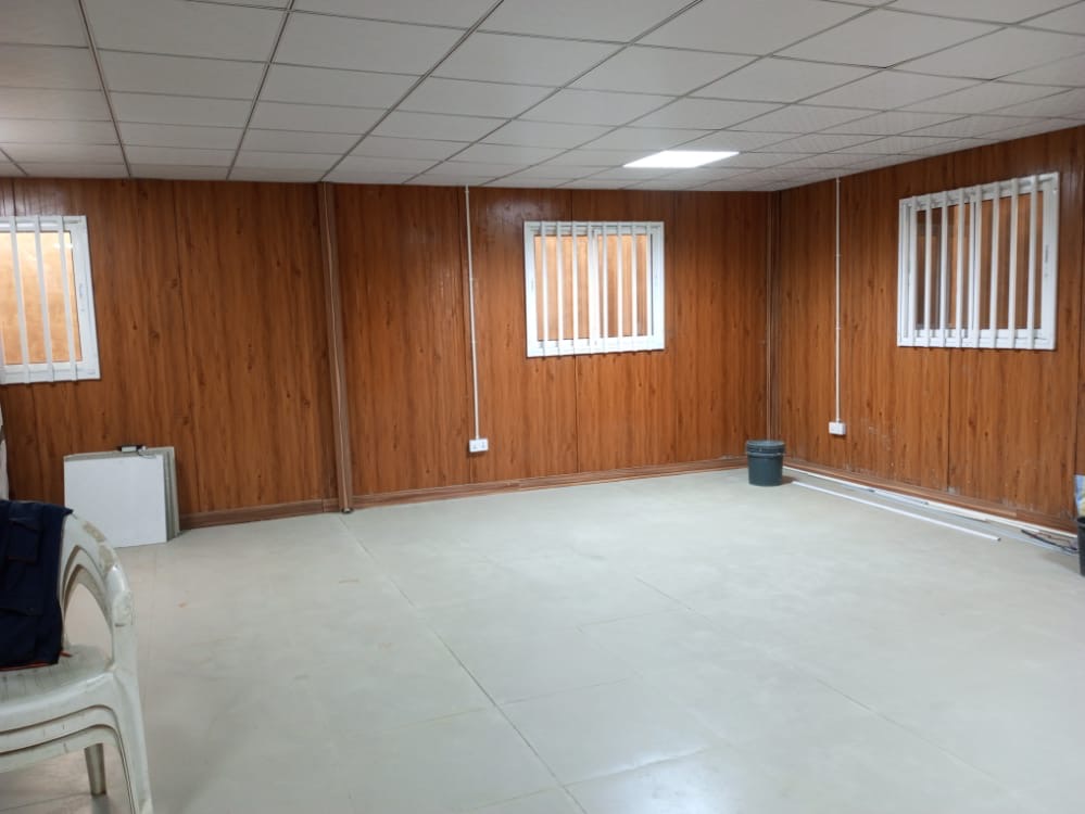 Interior of a finished container unit with wood-panel walls and ceiling grid